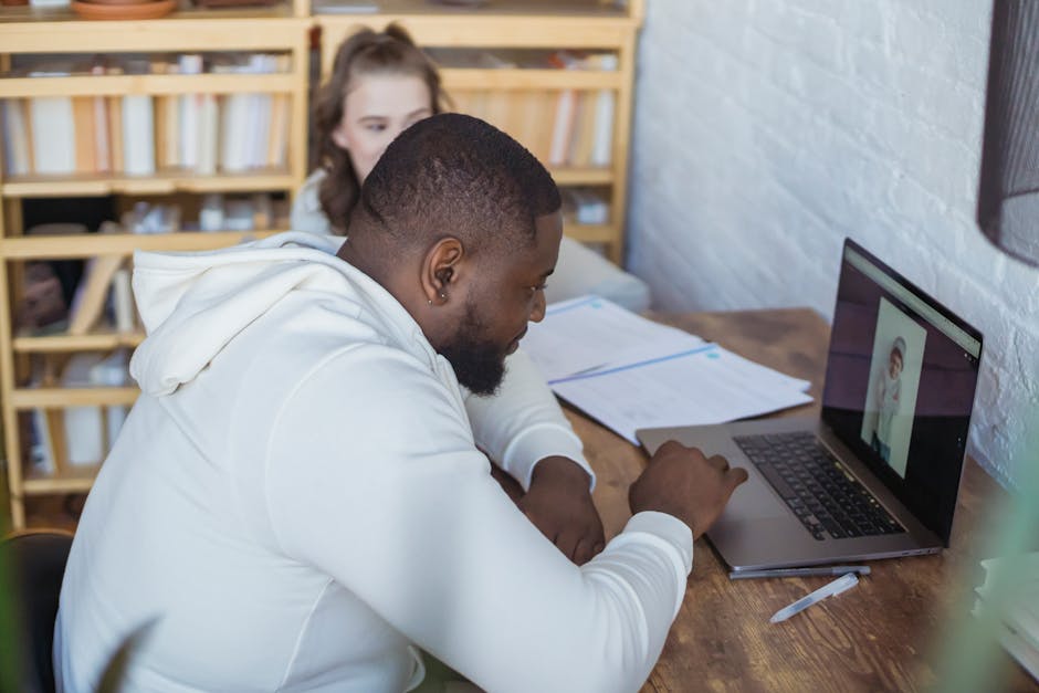 Side view of concentrated African American male freelancer sitting at table and working on netbook during remote work